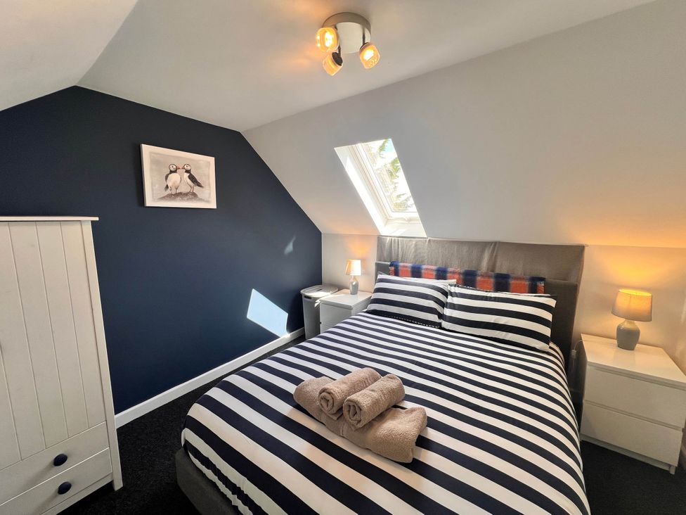A bedroom with a double bed and striped bedding at Cottage with mountain and sea views, Anglesey
