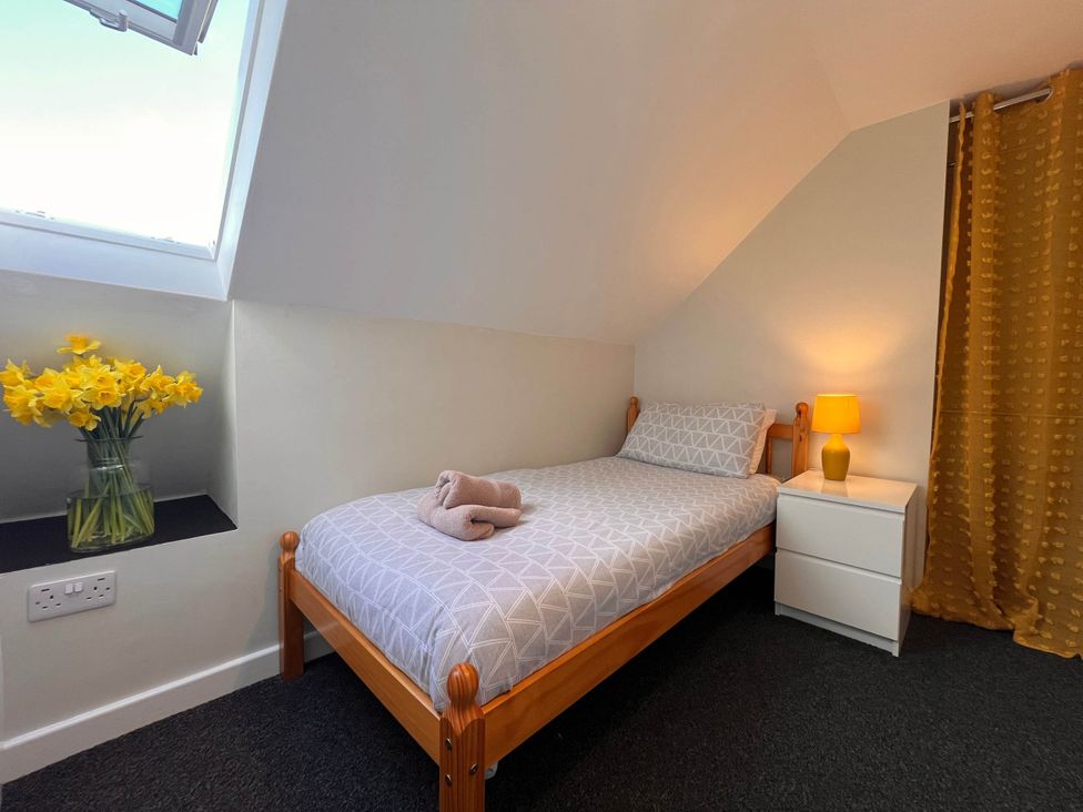 A bedroom with a bed and a flower vase at Cottage with mountain and sea views, Anglesey