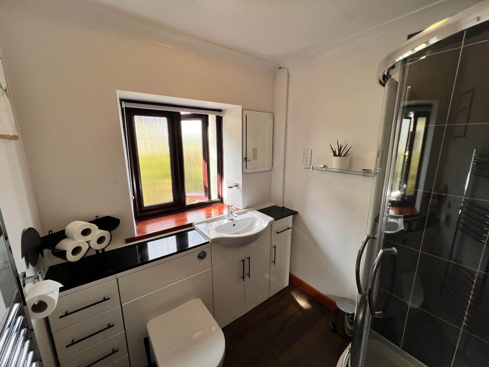 A bathroom with a sink, toilet, and shower at Cottage with mountain and sea views, Anglesey