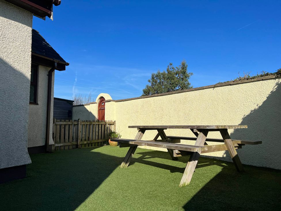 A garden with a wooden table and fence at Cottage with mountain and sea views, Anglesey