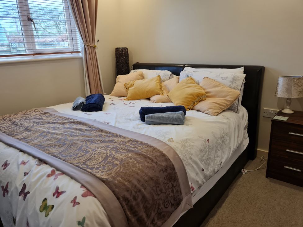 A bedroom with a bed and decorative pillows at Riverside cottage with otters near Tintagel