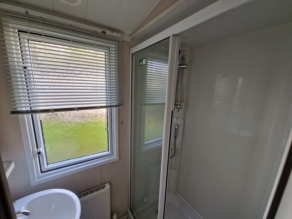 A bathroom with a shower cubicle and sink at Beach holiday base with pool and kids' activities