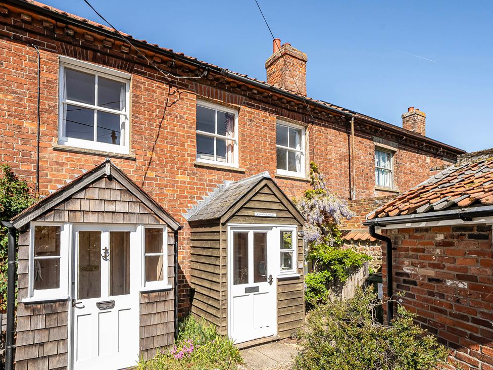 An outdoor area with wooden doors and brick walls at Coastal cottage near harbour, beach and pubs in Brancaster