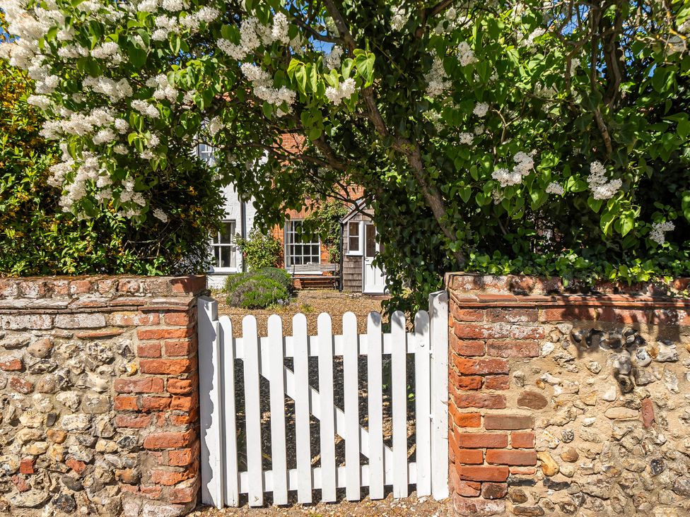 A garden with a white gate and brick wall at Coastal cottage near harbour, beach and pubs Brancaster