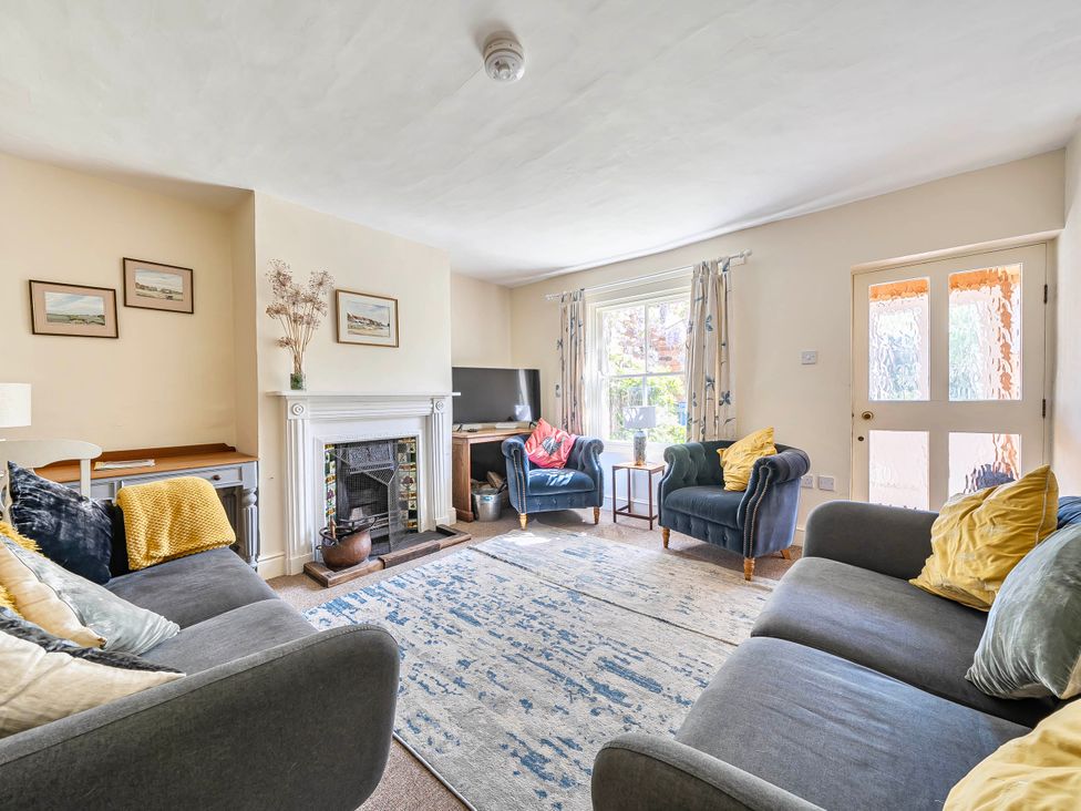 A living room with a sofa and armchairs near a fireplace at Coastal cottage near harbour, beach and pubs in Brancaster