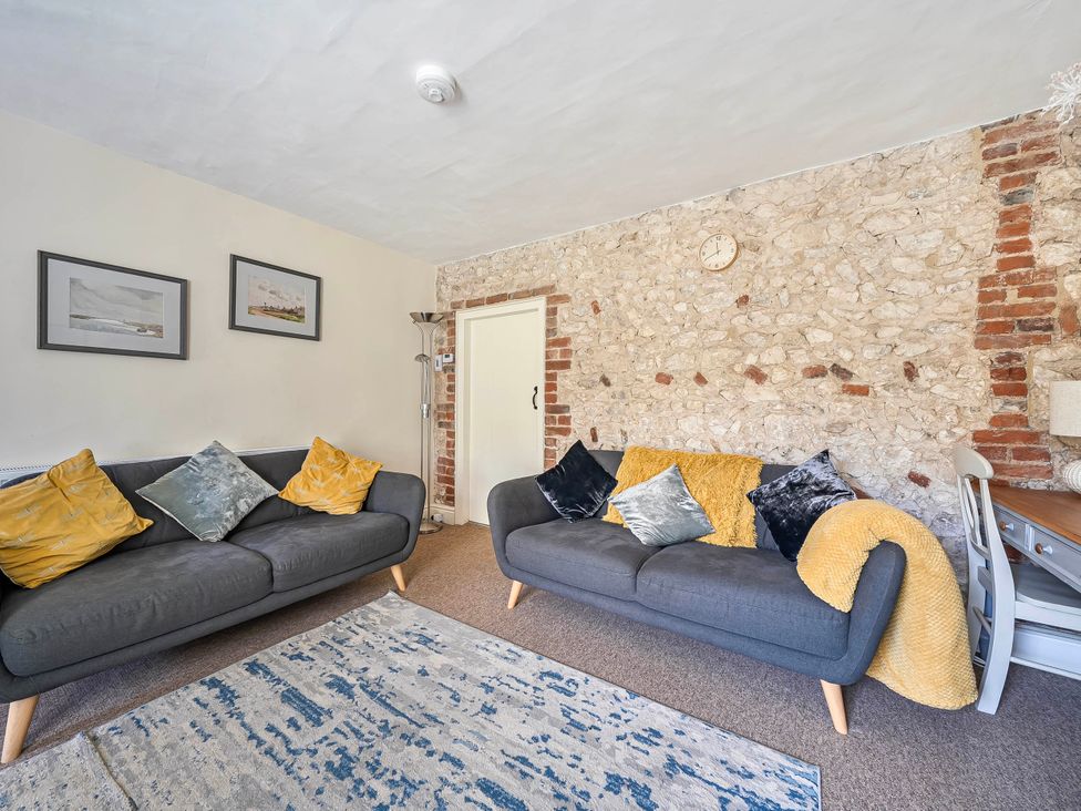 A living room featuring two sofas, a table, and wall art at Coastal cottage near harbour, beach and pubs, Brancaster