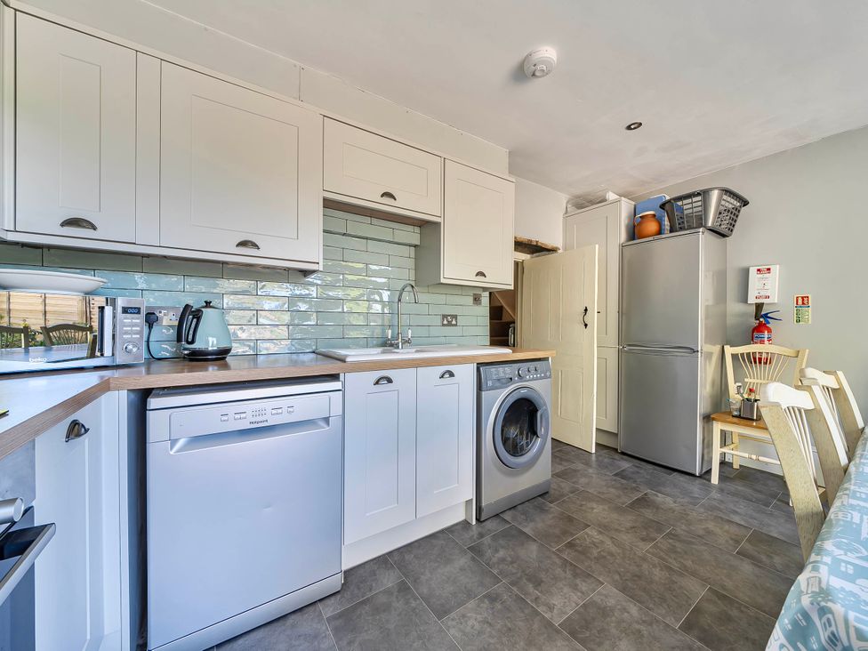 A kitchen with appliances and furniture at Coastal cottage near harbour, beach and pubs Brancaster