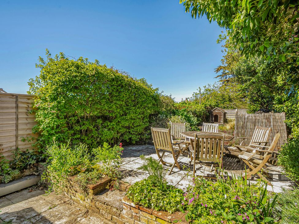 A garden with a wooden table and chairs at Coastal cottage near harbour, beach and pubs Brancaster