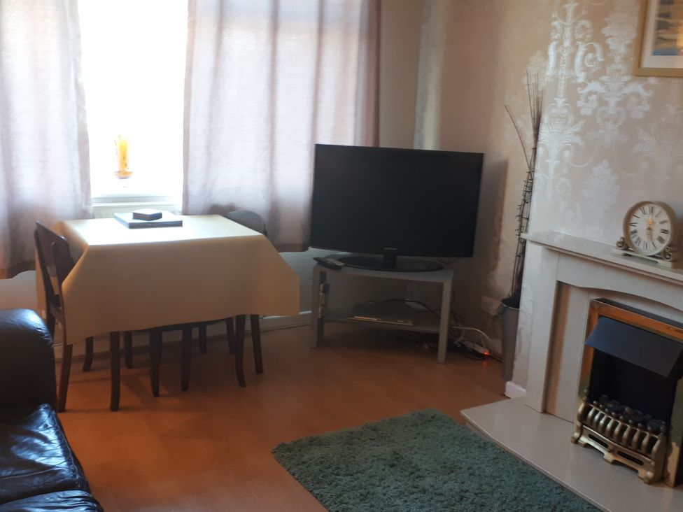 A living room with a sofa, table, television, and fireplace at tbc in 