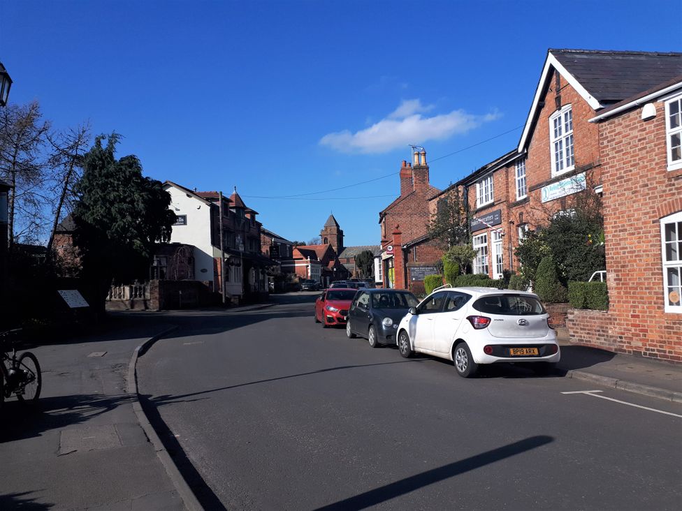 A street scene with buildings and parked cars at tbc