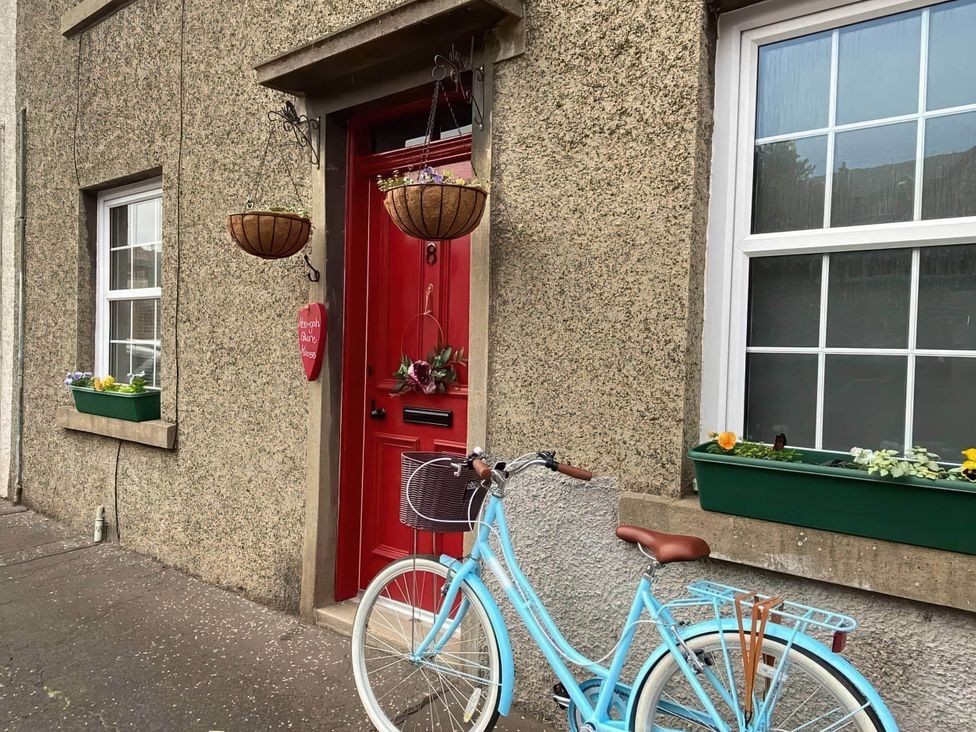 A front entrance with a red door and bicycle at Pet-friendly coastal flat with fire pit and views Newburgh, Fife