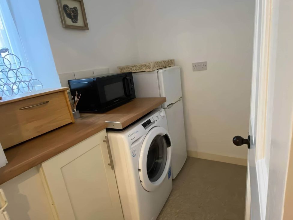 A utility room with a washing machine and refrigerator at Pet-friendly coastal flat with fire pit and views, Newburgh, Fife