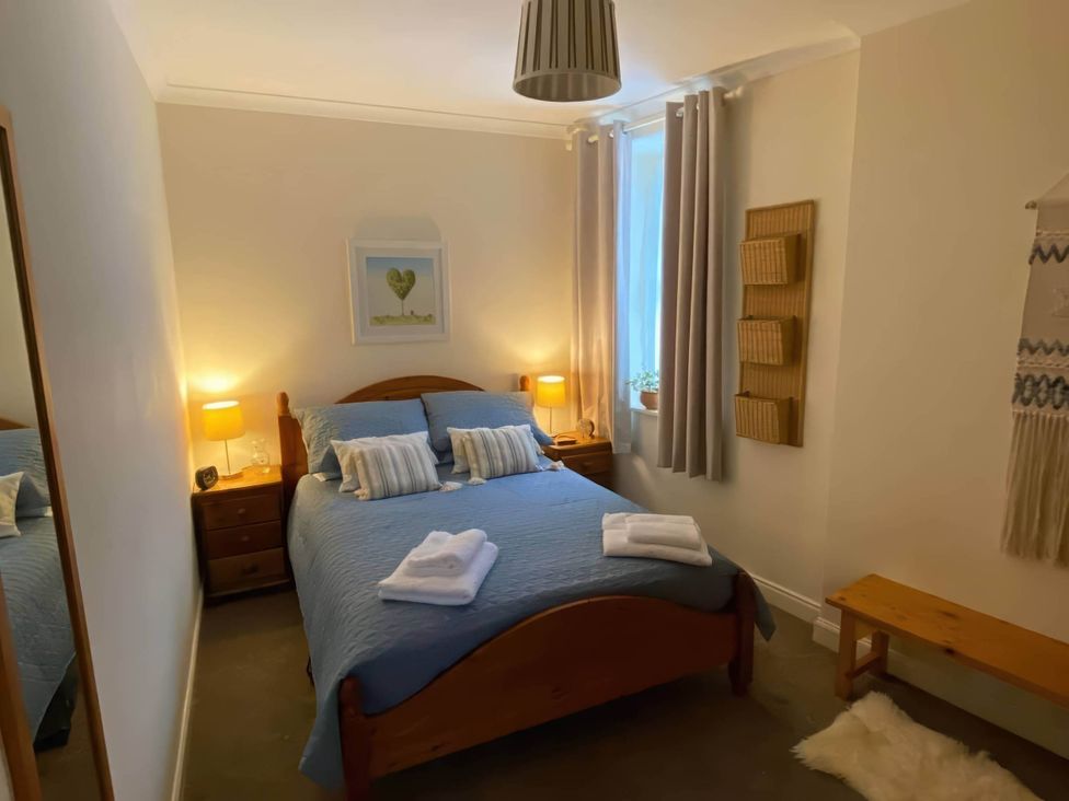 A bedroom with a bed, nightstand, lamps and curtains at Pet-friendly coastal flat with fire pit and views Newburgh, Fife