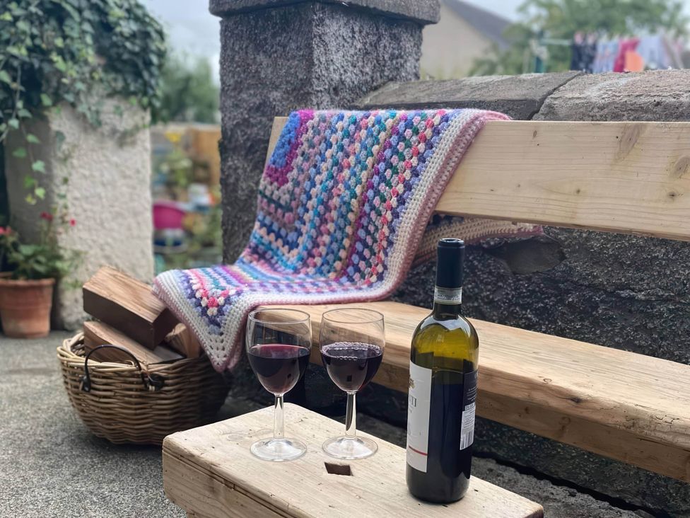 A wooden bench with a blanket and wine glasses at Pet-friendly coastal flat with fire pit and views in Newburgh, Fife