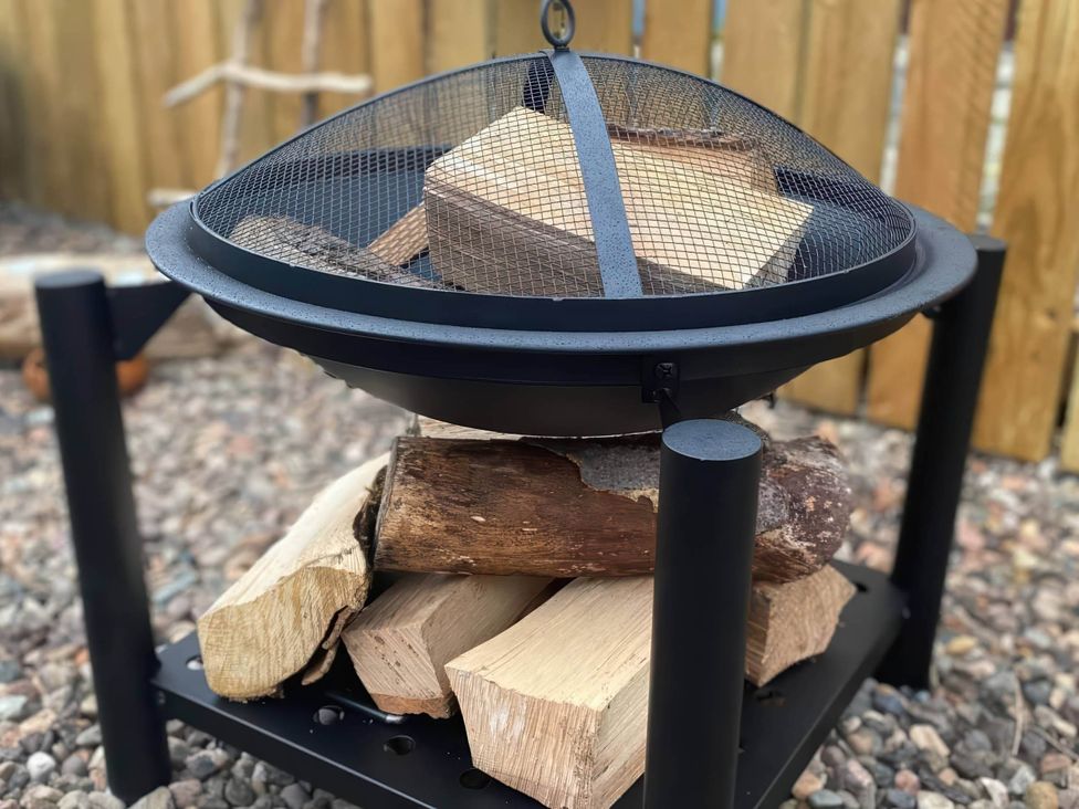 A fire pit with logs and a mesh cover at Pet-friendly coastal flat with fire pit and views, Newburgh, Fife