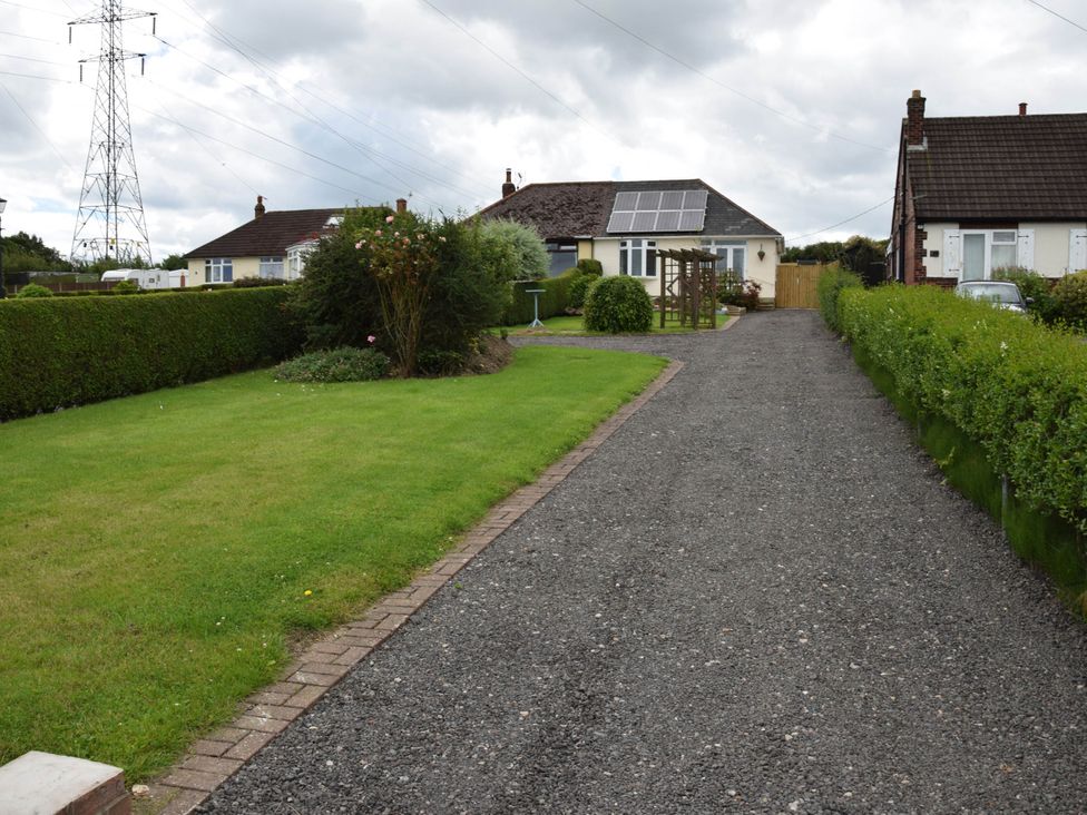 A garden with driveway and two houses at tbc