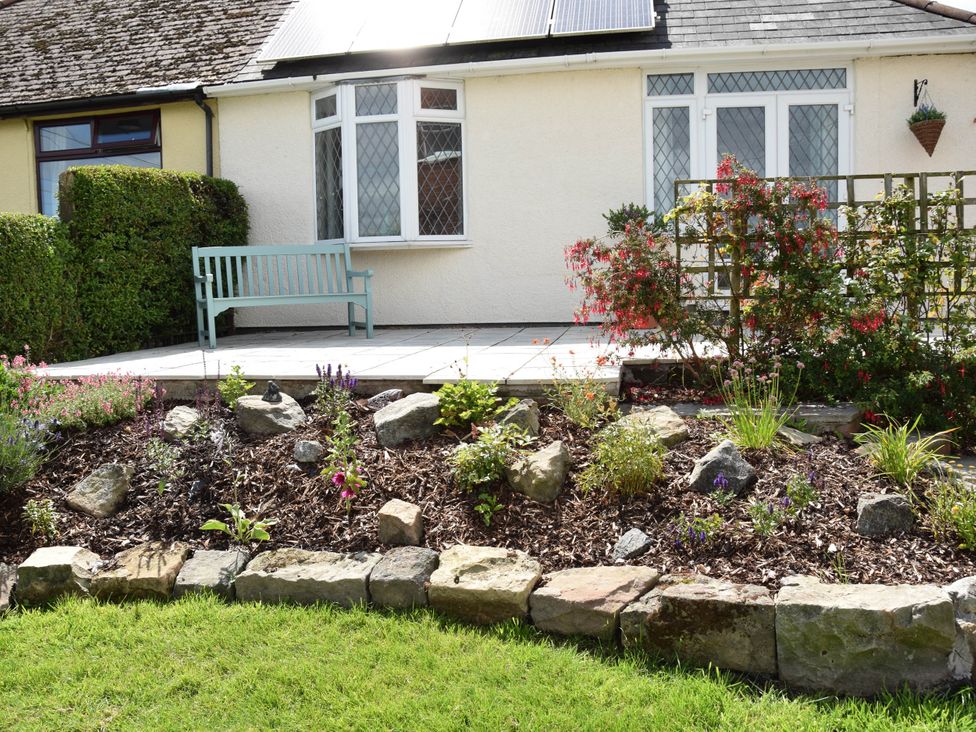 A garden with a bench and flowerbed at tbc
