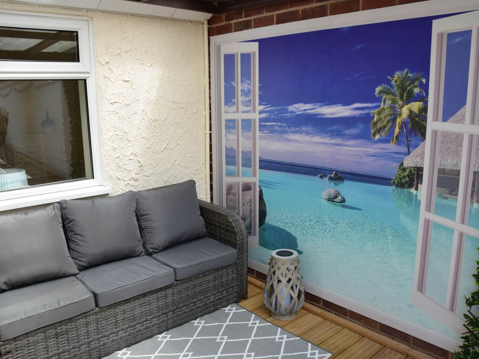 A snug with a grey sofa and a wall mural depicting a beach scene at tbc
