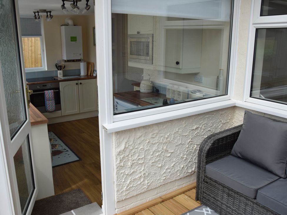 A conservatory with a view of a kitchen and a chair at tbc in 