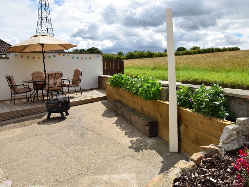 A garden with a table and chairs under an umbrella at tbc in 