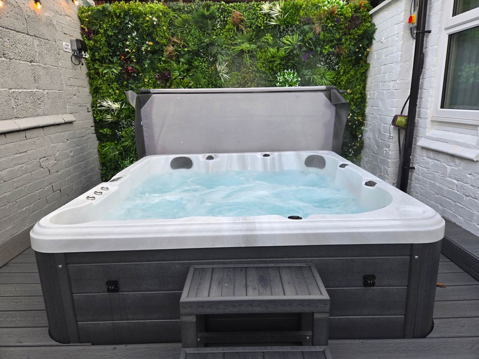 A hot tub with water and steps in an outdoor area at tbc