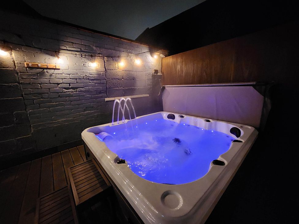 A hot tub with water jets and lighting in an outdoor area at tbc