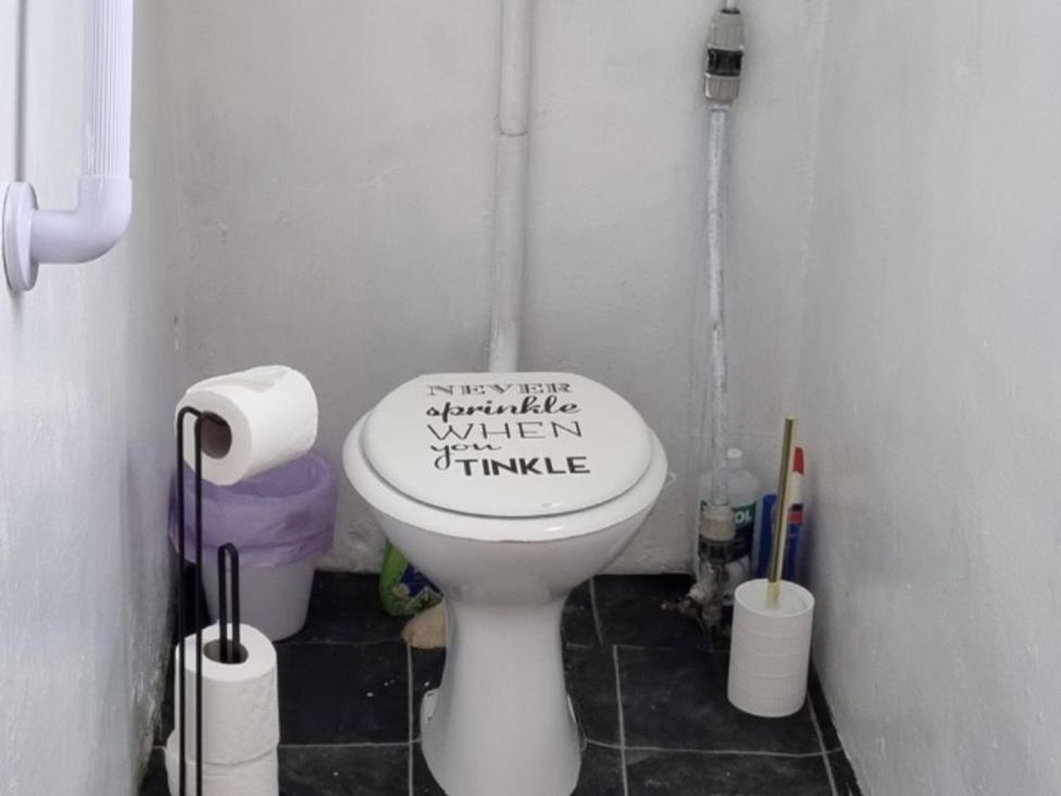 A bathroom with a toilet and toilet paper holder at tbc