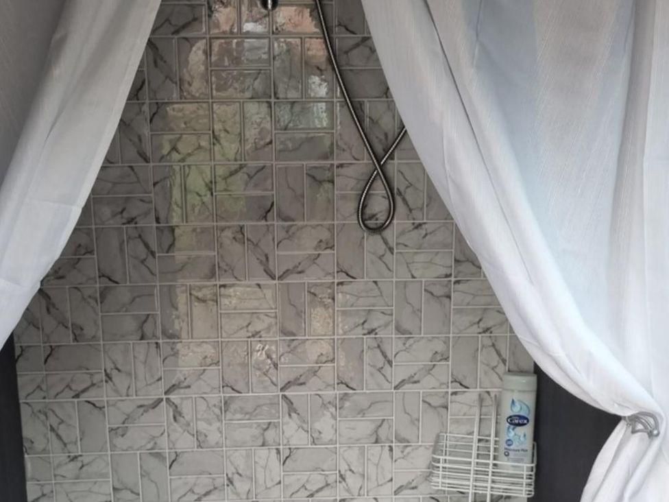 A shower area with tiles and a shower caddy at tbc