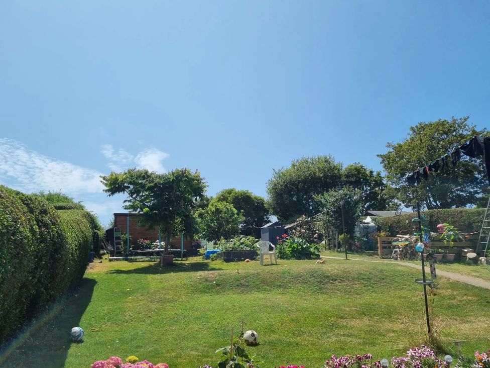 A garden with flowers, trees, a shed, and a soccer ball at tbc