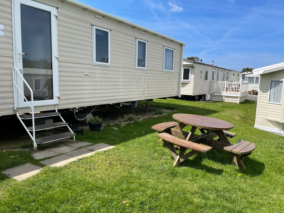 A picnic table with benches next to a caravan at tbc in 