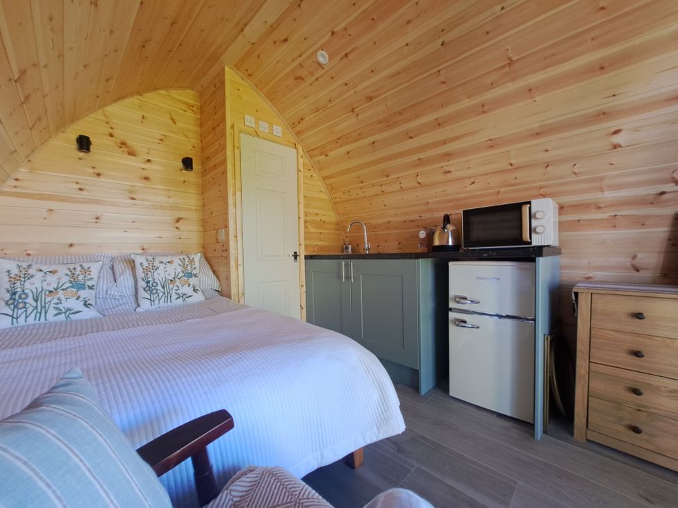 A bedroom with a bed and small kitchen area at tbc