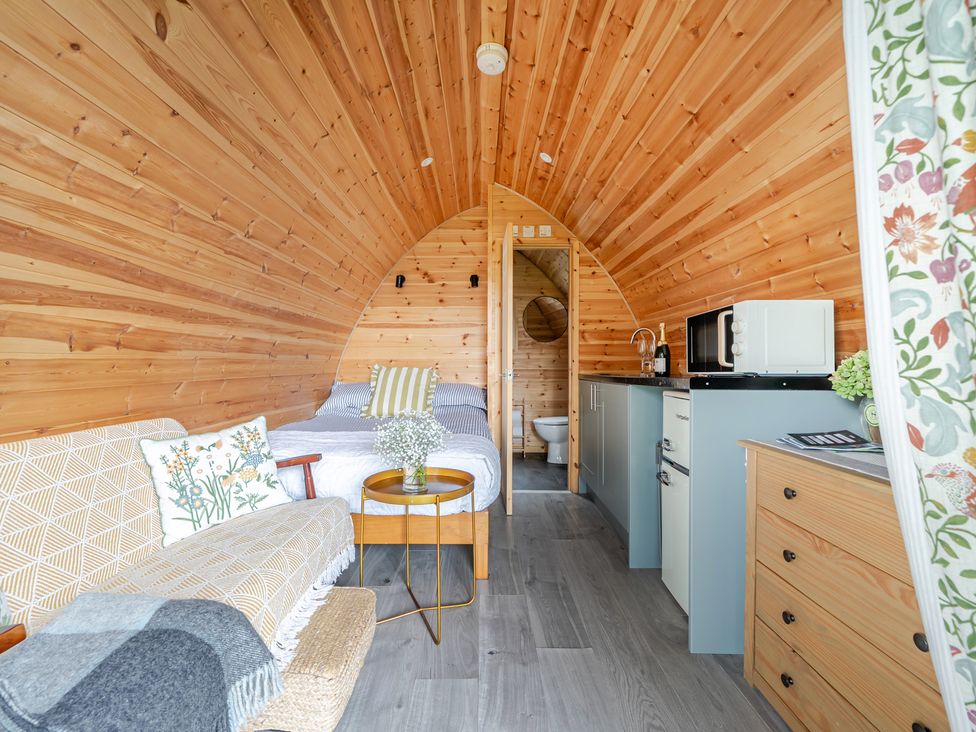 A bedroom with a bed and kitchenette at Peaceful pod with bay views, walk to 3 beaches St Ives