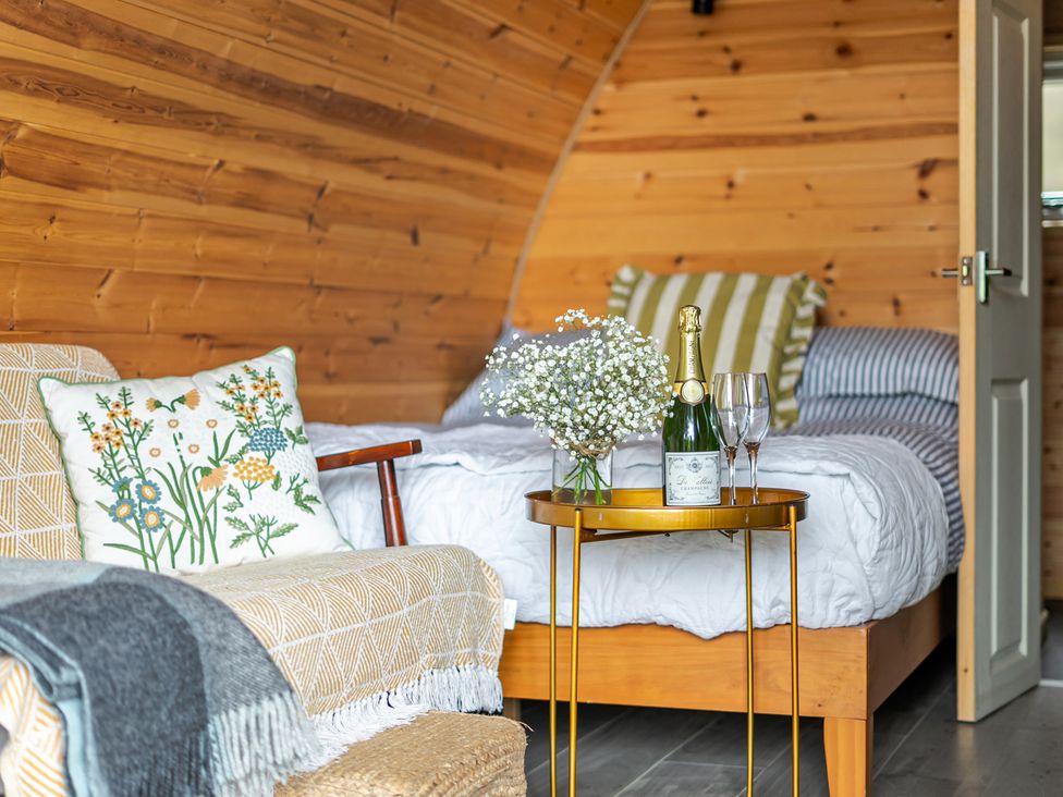 A bedroom with a sofa, bed, and champagne at Peaceful pod with bay views, walk to 3 beaches St Ives