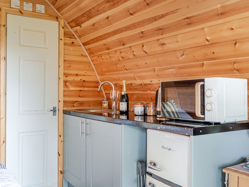 A kitchen with a sink, microwave, fridge, and champagne at Peaceful pod with bay views, walk to 3 beaches St Ives