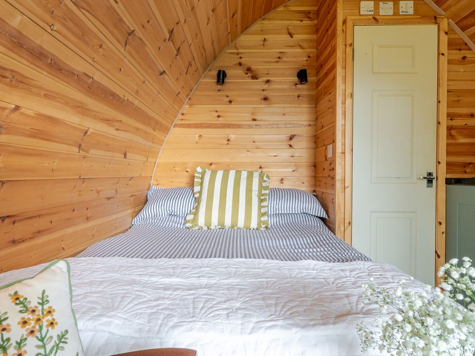 A bedroom with a bed and wooden wall at Peaceful pod with bay views, walk to 3 beaches, St Ives