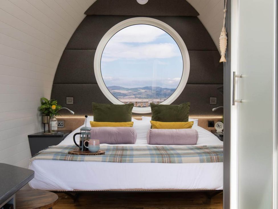 A bedroom with a round window and a bed with pillows at tbc