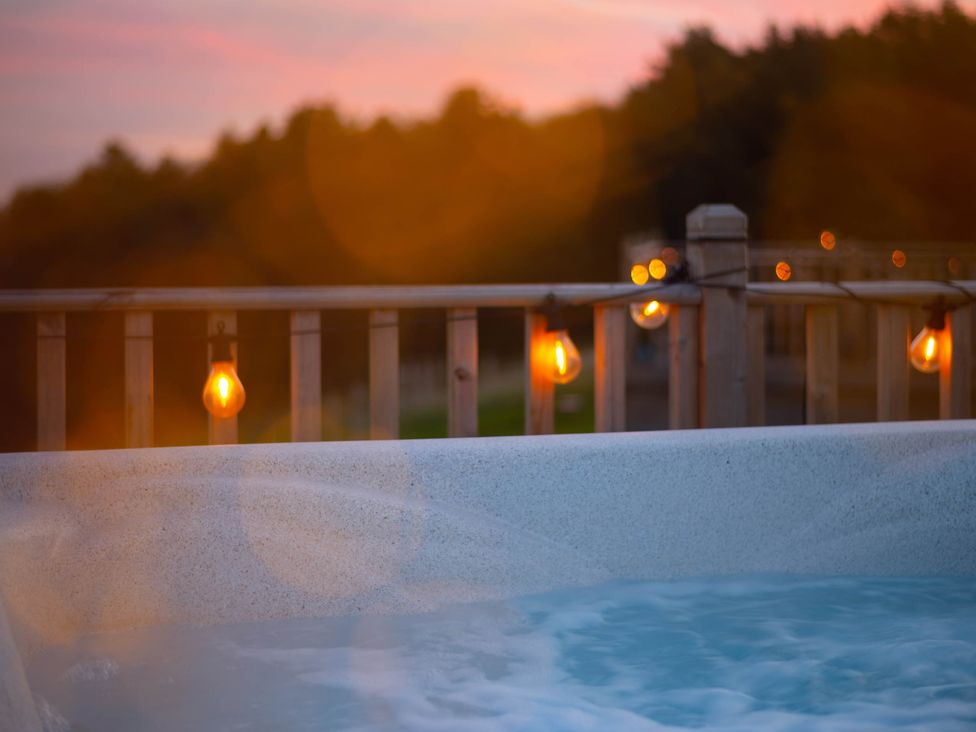 A hot tub with a railing and string lights at tbc 