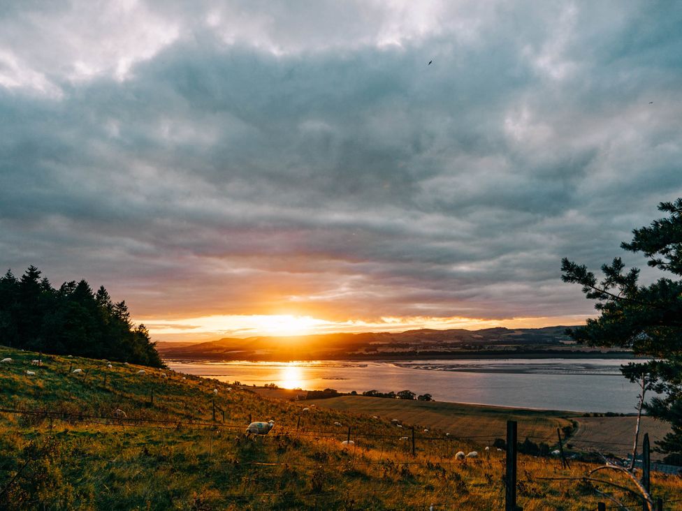 A sunset over a river with hills and sheep at tbc