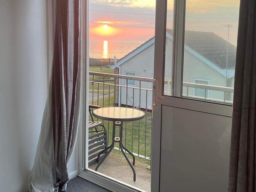 A balcony view with a table and chairs overlooking the sea at The Old Barn in 