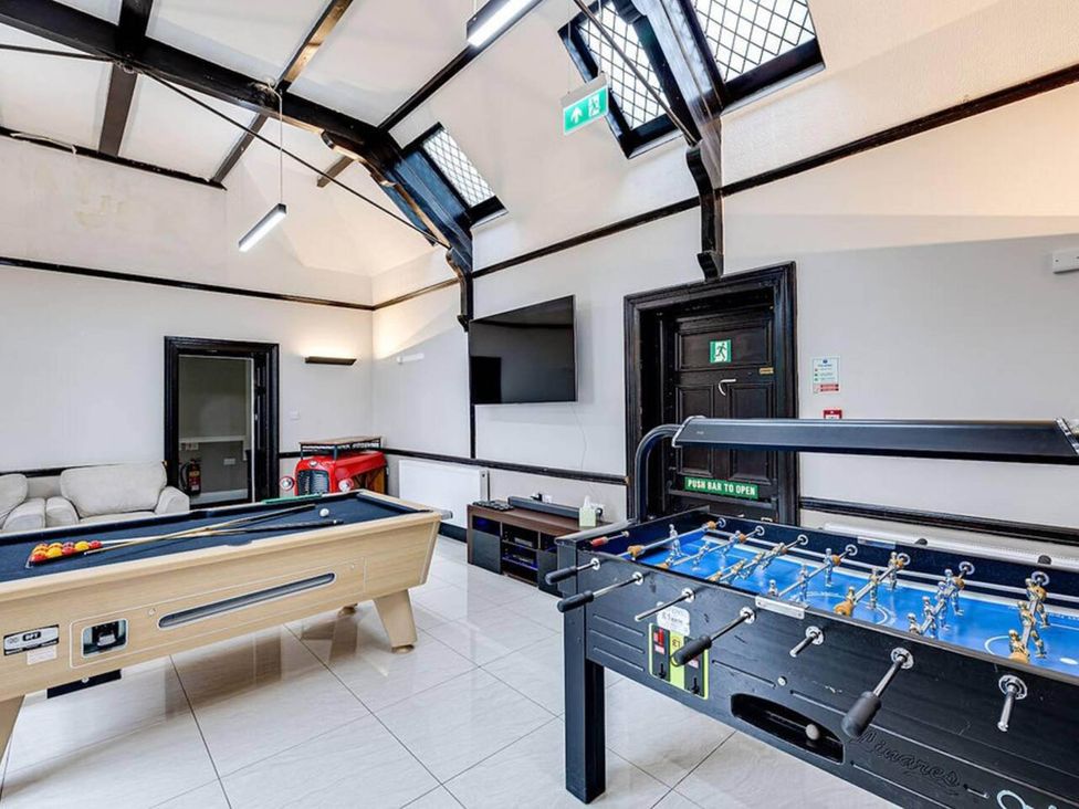 A game room with a pool table and foosball table at tbc