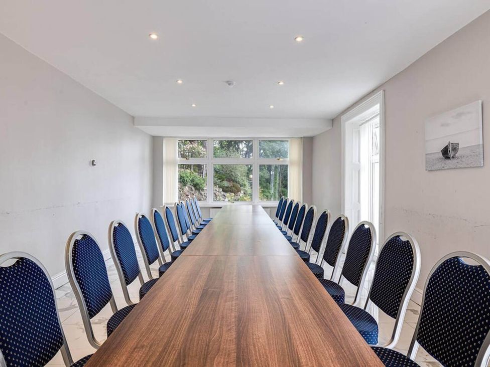 A conference room with a long table and chairs at tbc