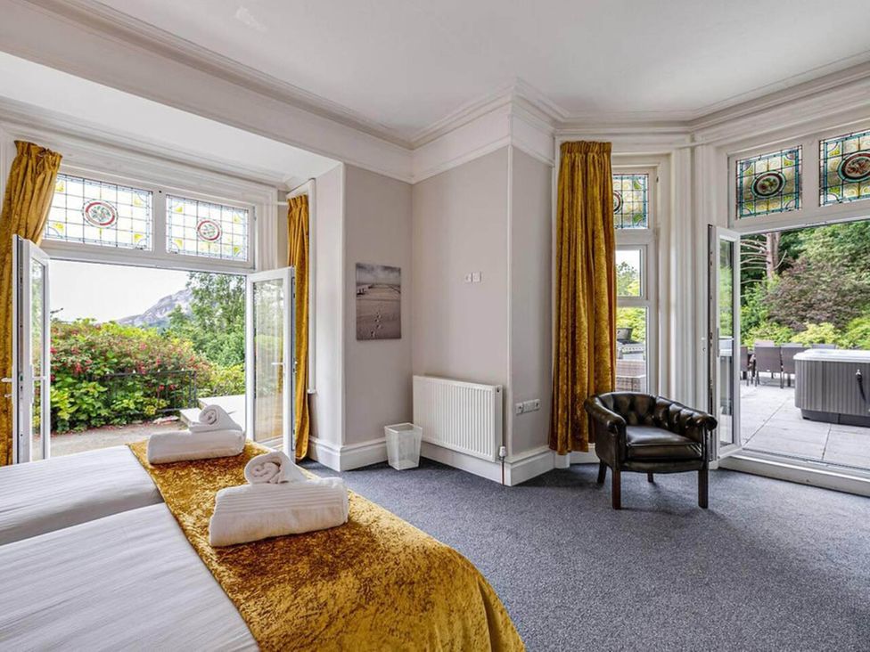 A bedroom with a bed and windows leading to outdoor seating at tbc