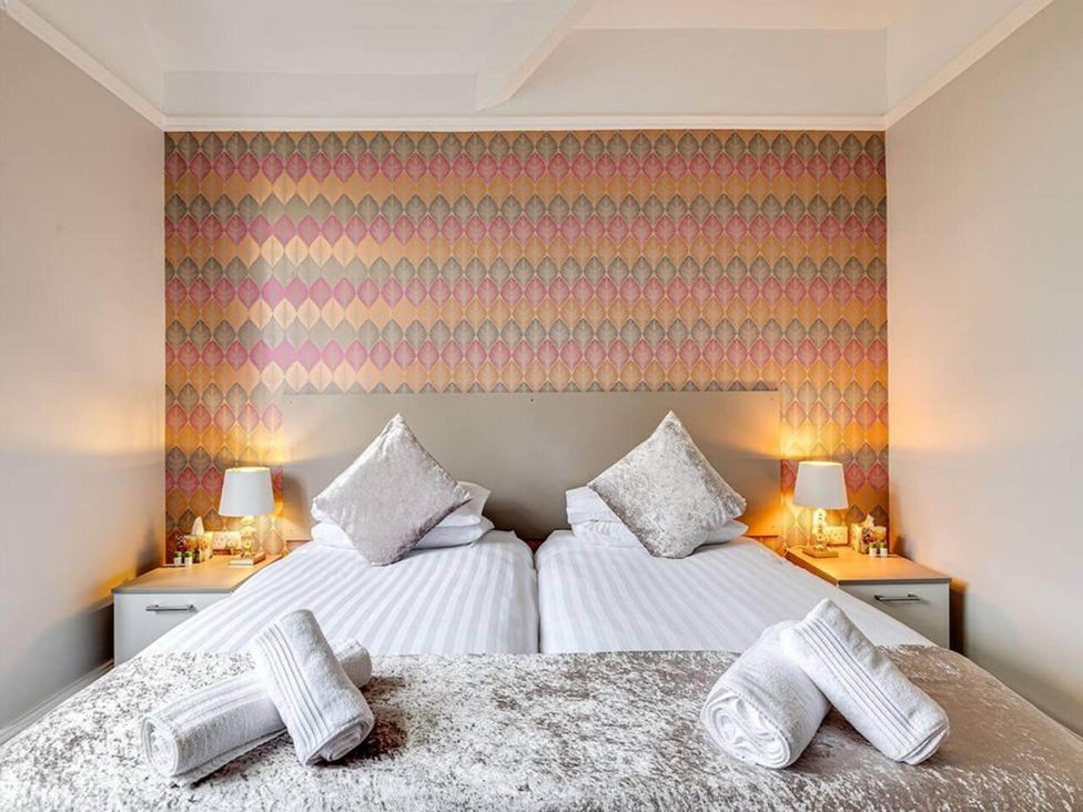 A bedroom with two beds and bedside lamps at tbc 