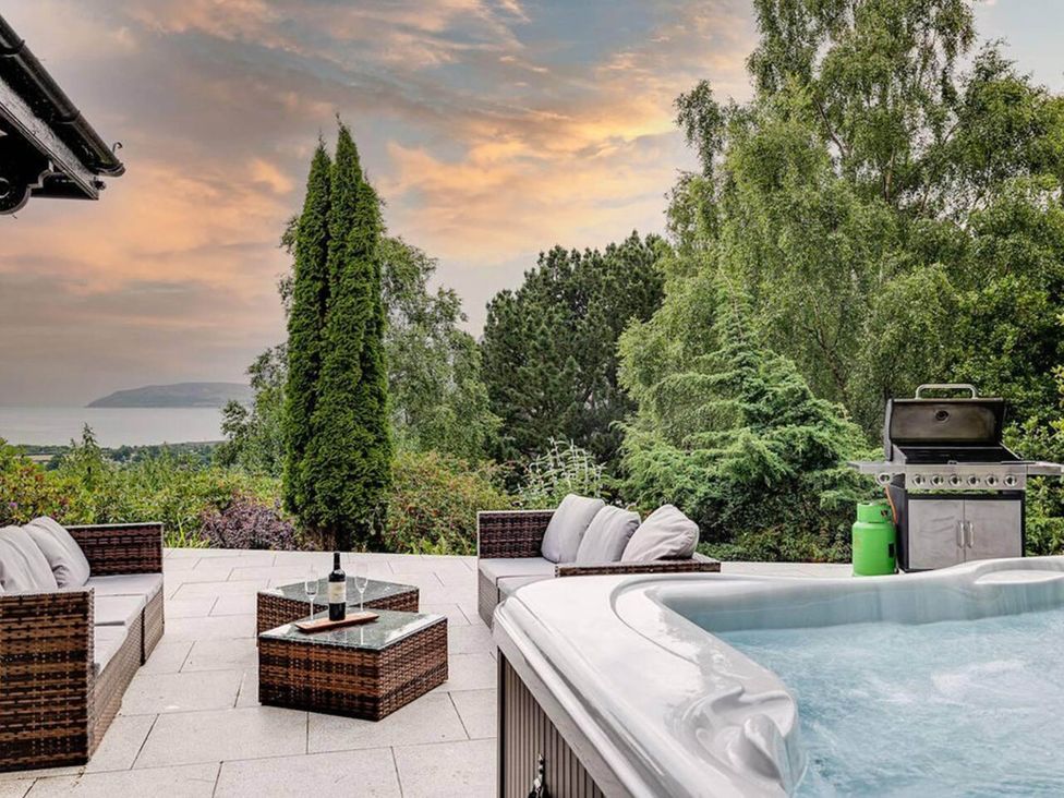 A patio with a hot tub and outdoor seating at tbc