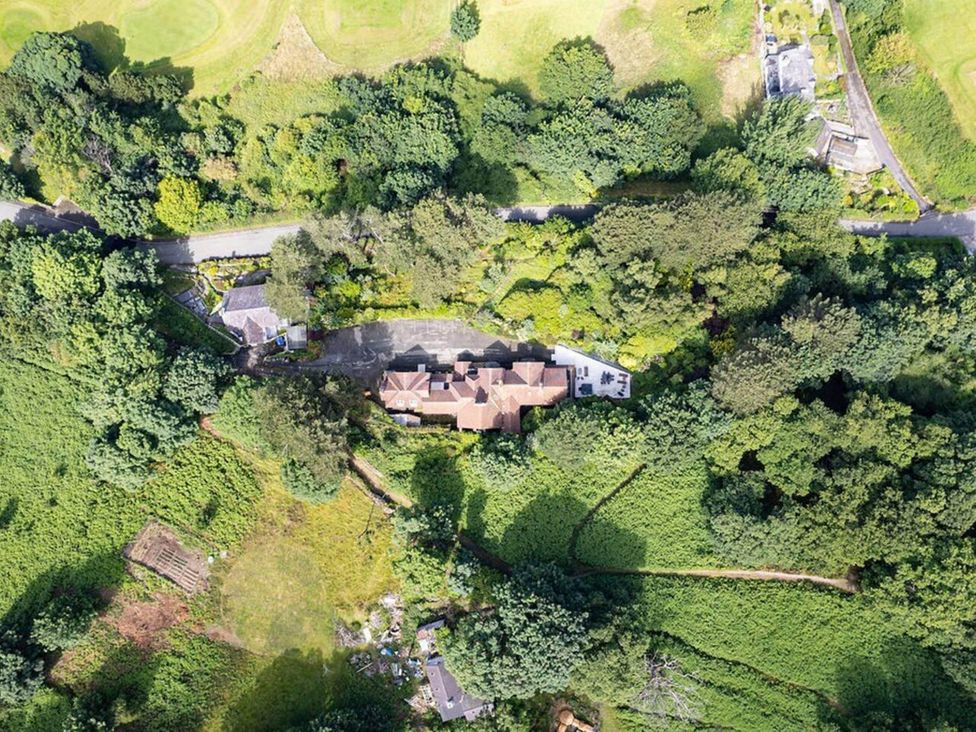 An aerial view of a house surrounded by trees and a road at tbc