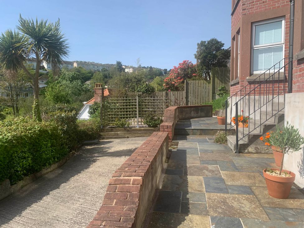 An outdoor garden with a stone pathway and flower pots at tbc 