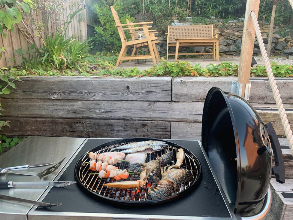 A grill with seafood cooking at a backyard with patio furniture at tbc
