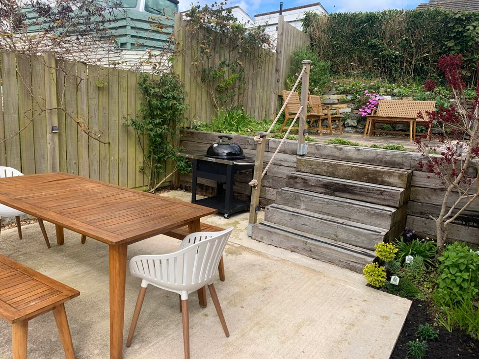 A garden with a dining table and chairs and a barbecue grill at tbc