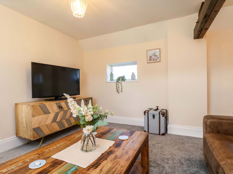 A living room with a television and a flower arrangement at Lamb Cottage Stockton-On-Tees
