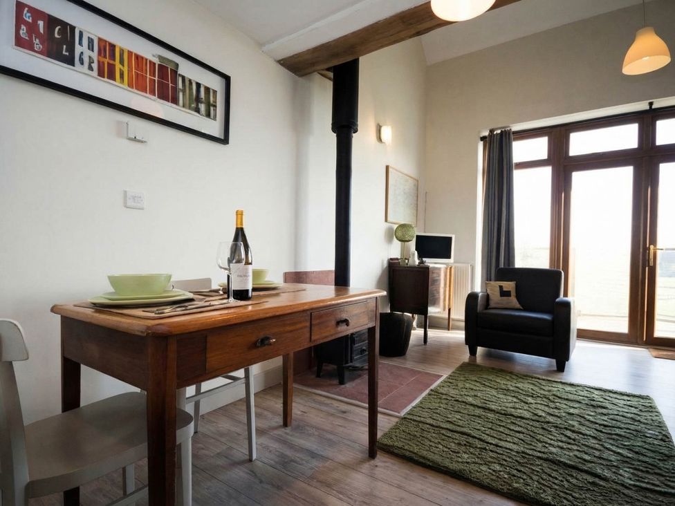 A dining room with a table and chairs at Countryside cottage with wood fire near the coast
